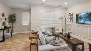 A living room with a sofa, a coffee table, and a TV mounted on the wall.