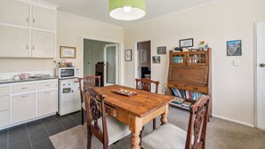 A kitchen with a wooden table, white cabinets, a microwave, and a green ceiling light. - Riverside Retreat in beautiful Arrow Junction (Arrow Junction)