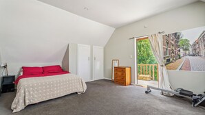A bedroom with a bed, a dresser, a mirror, and a view of a street through a window. - Riverside Retreat in beautiful Arrow Junction (Arrow Junction)