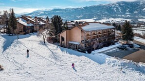 Une station de ski comprenant plusieurs bâtiments, dont un grand chalet doté d’un toit en pente et une construction plus petite avec un toit plat.