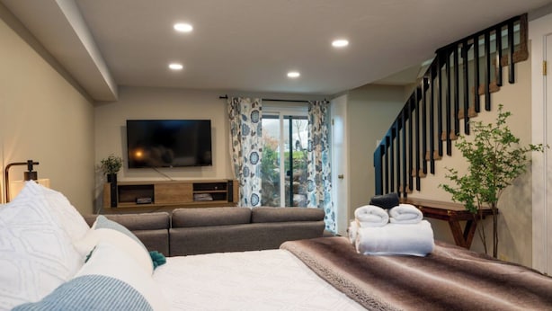 Une chambre moderne avec un grand lit, un canapé, une télévision et un escalier.