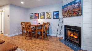 Un coin repas avec une table et des chaises en bois, une cheminée et un mur orné de tableaux.