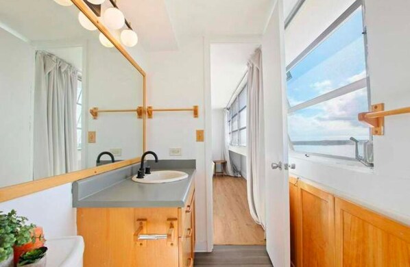 A compact bathroom with a sink, mirror, and wooden cabinets.