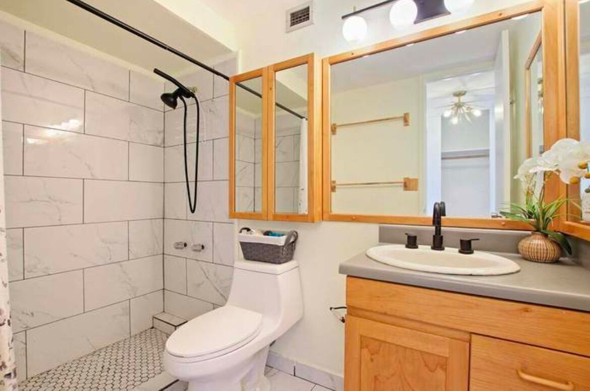 A bathroom with a shower, toilet, and vanity with a mirror.