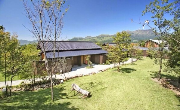 A traditional Japanese-style house with a sloped roof, surrounded by a well-maintained lawn and trees. - oyado daikonya (Takamori)