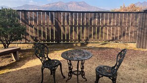 Un patio con due tavoli e sedie in metallo, una recinzione in legno e vista sulle montagne.