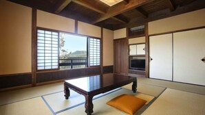 Una tradizionale stanza giapponese con pavimento in tatami, un tavolino in legno, porte scorrevoli e vista sull'esterno.