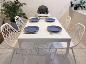 Une table à manger avec quatre chaises, une chaise haute et une plante en pot.