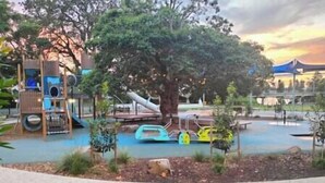 A playground with slides and climbing structures, surrounded by trees and a sandy area. - Central location | Alfresco dine on huge terrace | Walk to cafes/shops/blowhole (Kiama)