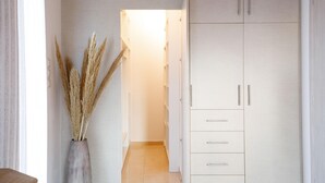 A hallway with a tall cabinet, a vase with dried plants, and a door leading to another room.