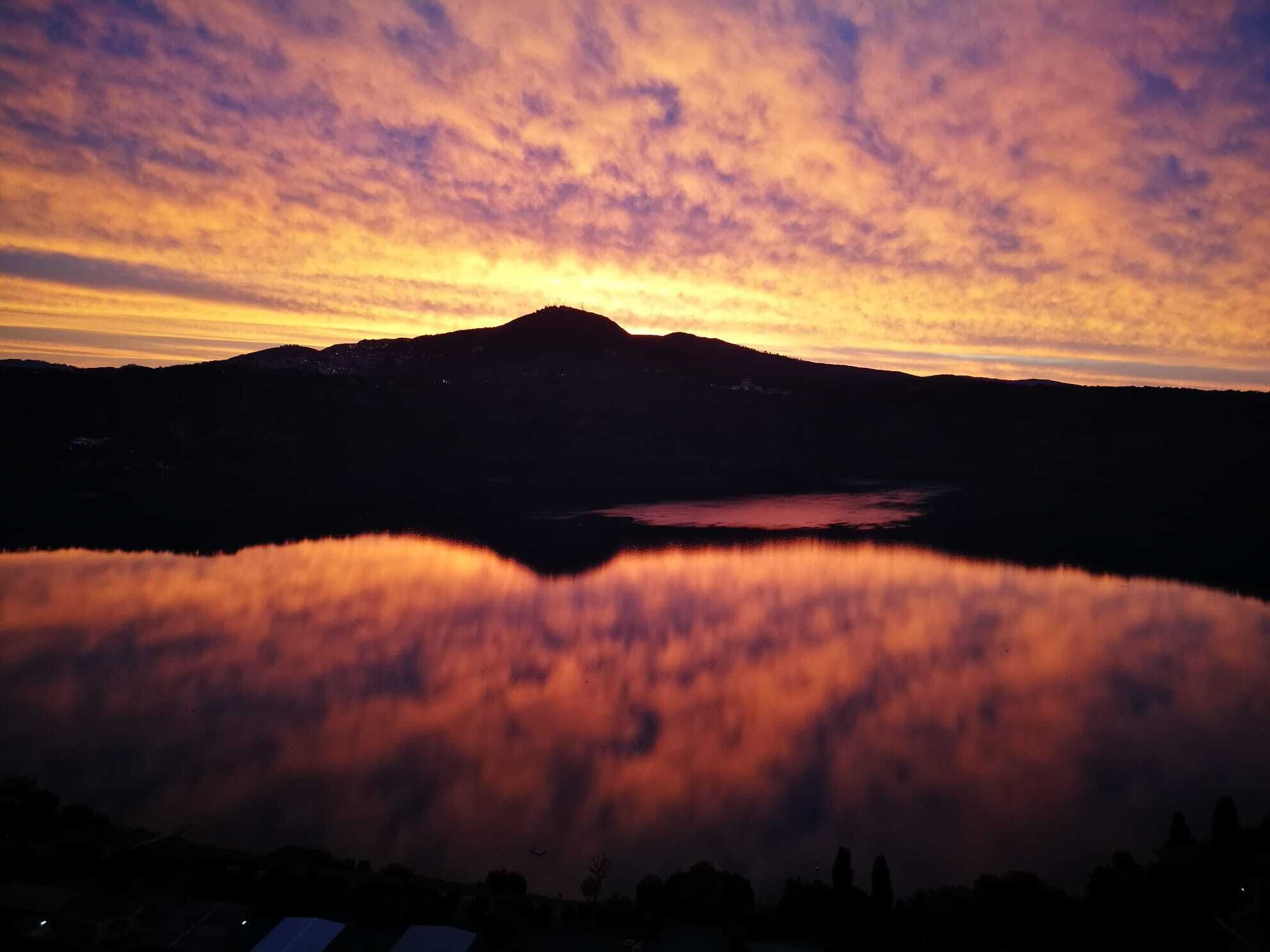 Silhueta de montanha refletida em um lago calmo ao pôr do sol.