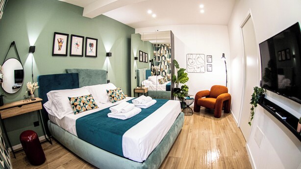 Una habitación de hotel moderna con una cama grande, televisión, escritorio y silla.