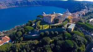 Vista aérea de un complejo de edificios históricos con un gran lago al fondo.