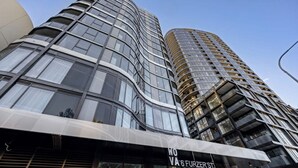 A modern building with curved glass windows and a sign reading "WOVA 6 FURZER ST." - Modern 1 Bedroom Apartment in Philip Canberra (Phillip)