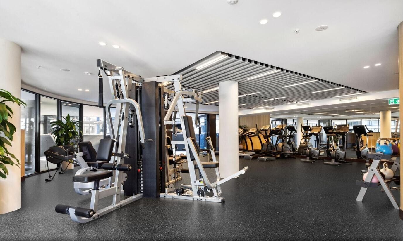 A modern gym with various exercise equipment, including weight machines and cardio machines.