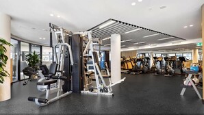 A modern gym with various exercise equipment, including weight machines and cardio machines. - Modern 1 Bedroom Apartment in Philip Canberra (Phillip)