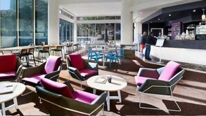 A spacious indoor seating area with modern chairs and tables, large windows offering views of the cityscape, and a bar counter visible in the background. - Ocean View King Bed Studio | Steps to Beach and Tram (Surfers Paradise)