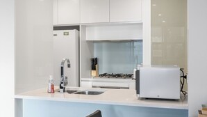 Een moderne keuken met witte kasten, een roestvrijstalen spoelbak, een inbouwfornuis en een broodrooster.