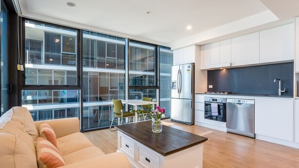 A modern kitchen with white cabinets, a stainless steel refrigerator, and a built-in dishwasher. - High Floor River View 1BR Prime Location w/Parking (South Brisbane)