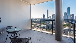 A balcony with a table and chairs, offering a city view. - High Floor River View 1BR Prime Location w/Parking (South Brisbane)