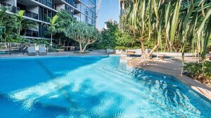 A swimming pool surrounded by palm trees and modern buildings. - High Floor River View 1BR Prime Location w/Parking (South Brisbane)