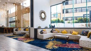 A modern hotel lobby with a large seating area, a dining area, and large windows offering views of the outside. - Cozy and Bright 2-bedroom Apartment in Surfers (Surfers Paradise)