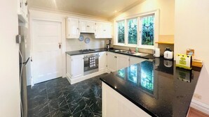 Een moderne keuken met witte kasten, een zwarte marmeren vloer en een raam met glas-in-lood.