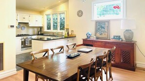 Een ruime keuken met witte kastjes, een centraal eiland en een eetgedeelte met een houten tafel en stoelen.