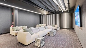A modern, well-lit room with a sectional sofa, a flat-screen TV, and a patterned wall.
