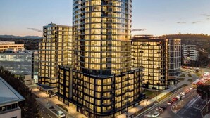 A modern, multi-story building with a curved facade, large windows, and a well-lit exterior.
