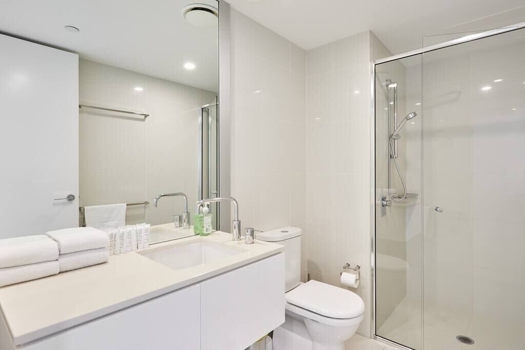 A modern bathroom with a glass shower enclosure, a white sink with a mirror, and a toilet.