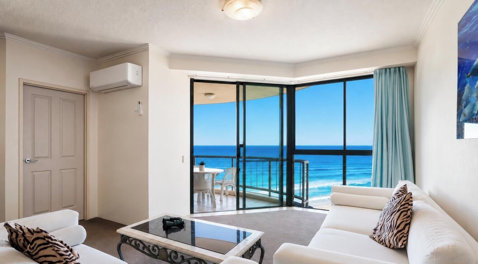Een hotelkamer met balkon, een sofa, een bijzettafeltje en uitzicht op zee.