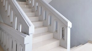 A staircase with white balustrades and a grey wall. - Djuragan Kamar Balawan (Malang)