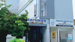 A modern building with a sign for 'BALAWAN' and another sign for 'PRAKTEK DOKTER GIGI'. - Djuragan Kamar Balawan (Malang)