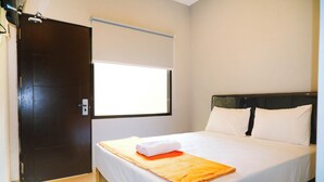 A hotel room with a bed, a window, and a door. - Djuragan Kamar Balawan (Malang)