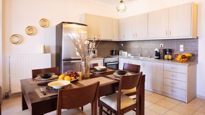 A modern kitchen with a dining table set for four, equipped with a refrigerator, stove, and various kitchen appliances.