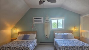 A bedroom with two beds, a ceiling fan, a surfboard, and a window. - Spacious 2 Bedroom Condo in North Ocean City! (Ocean City)