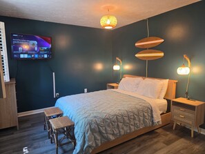 Un dormitorio con una cama, mesitas de noche, un televisor montado en la pared y un banco.
