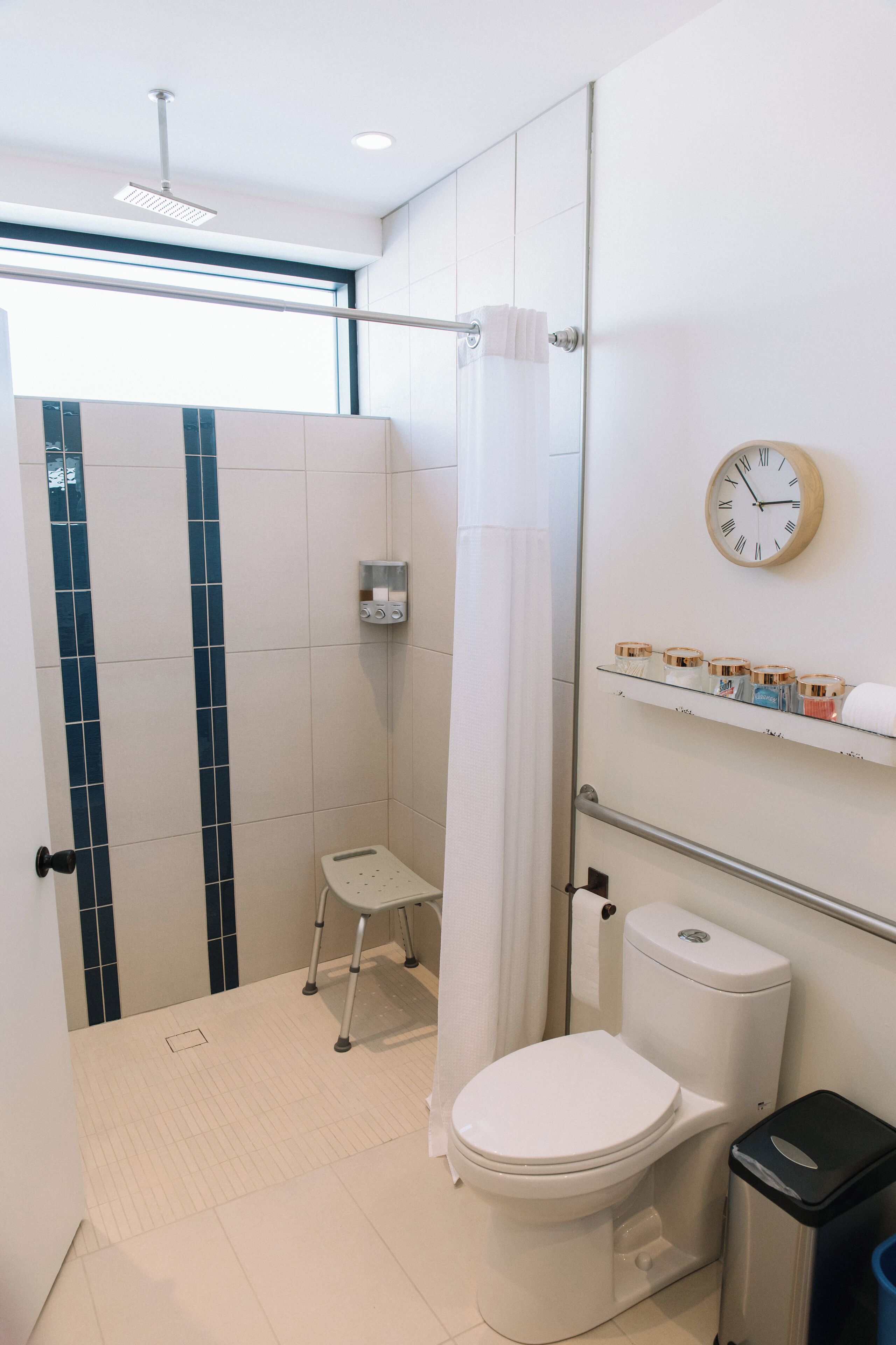 A modern bathroom with a shower, toilet, and a small step stool.