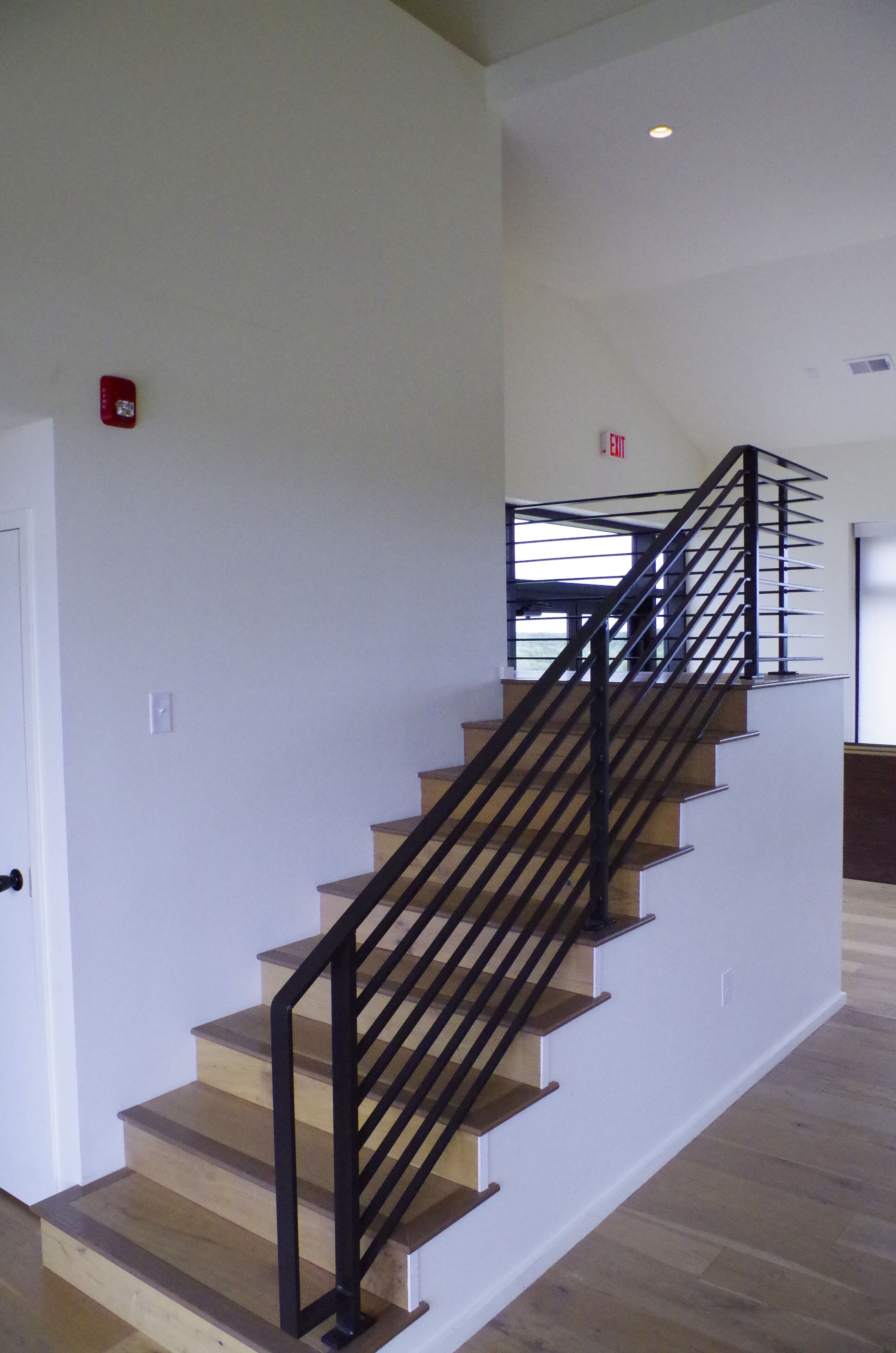 A staircase with wooden steps and black metal railings, leading to an upper floor.