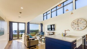 Eine moderne Küche mit einer großen Kochinsel, ein Essbereich mit Aussicht und ein Wohnzimmer mit Sofa und Couchtisch.