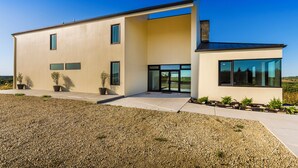 Ein modernes, zweistöckiges Haus mit Flachdach, großen Fenstern und einer Auffahrt mit Kies.