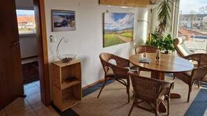 Un coin repas avec des meubles en osier, une table en bois et une vue sur l’extérieur.