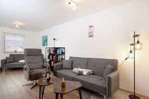 A living room with a grey sofa, a grey armchair, a wooden coffee table, and a floor lamp.