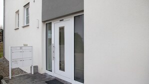 A building with a white exterior, a door with a glass panel, and a utility box.