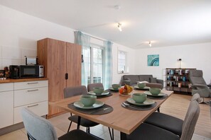 A modern kitchen with a microwave, wooden cabinets, and a dining area with green bowls and plates.