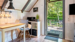 A modern kitchen with a wooden countertop, a bar stool, a hanging light fixture, and a view of the outdoors.