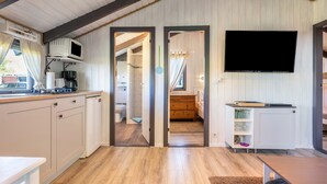 Habitació amb cuina, televisió penjada a la paret i entrada a un bany.