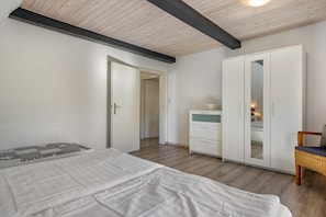 A bedroom with a bed, a wardrobe, a dresser, and a chair.