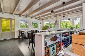 Eine Küche mit Holzbalken, einer Bar mit Barhocker und Blick ins Grüne.